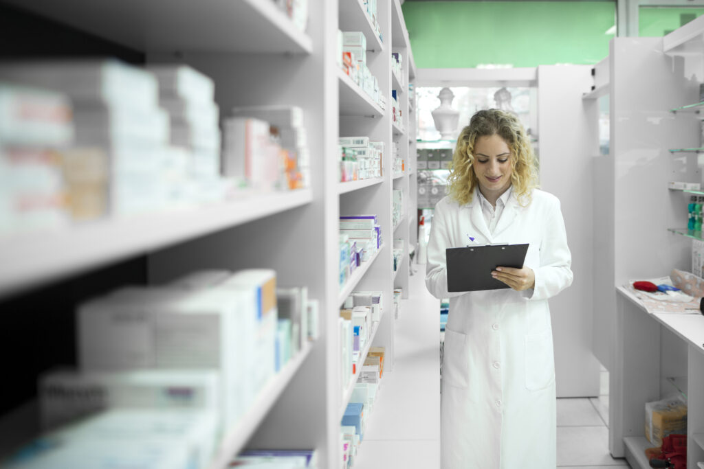 Pharmacist White Uniform Walking By Shelf With Medicines Checking Inventory 1024x683